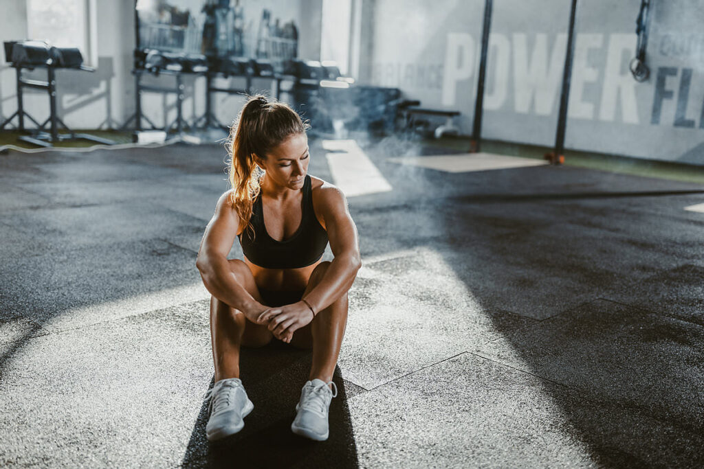 Girl sitting on the floor and recovering from a workout